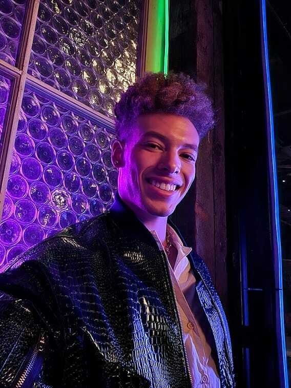 Un homme prend un selfie dans un lieu sombre avec des lumières colorées.  Son visage est lumineux et les couleurs sont...