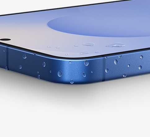 Gros plan sur le coin du Galaxy S25 plus avec des gouttelettes d’eau sur le cadre en aluminium.