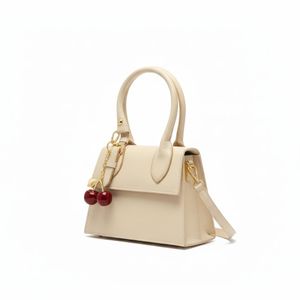 حقيبة كتف صلبة للسيدات بلون كريم/عاري. تصميم أنيق مع مقبض علوي، وحزام كتف قابل للإزالة، وسحر كرز ذواقة.